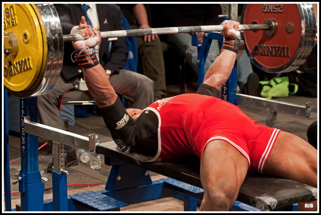 A powerlifter performing the barbell bench press during a powerlifting competition