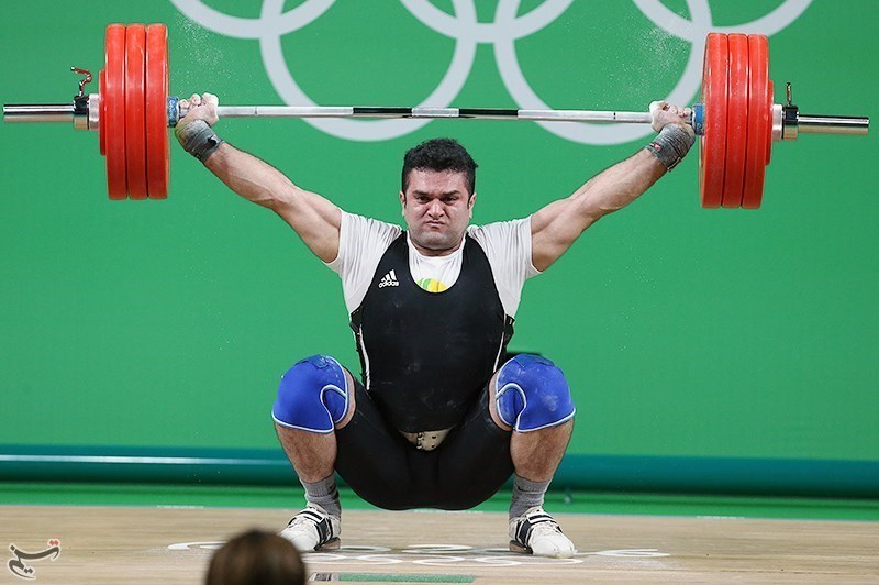 An Olympic weightlifter performing the barbell snatch at a weightlifting compeittion