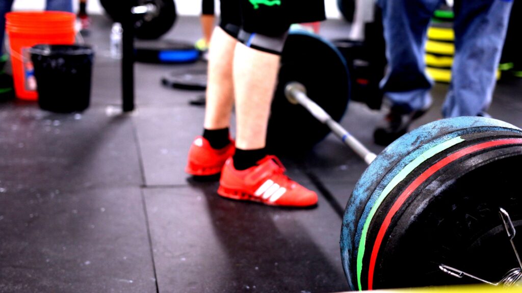 A lifter standing next to a loaded barbell