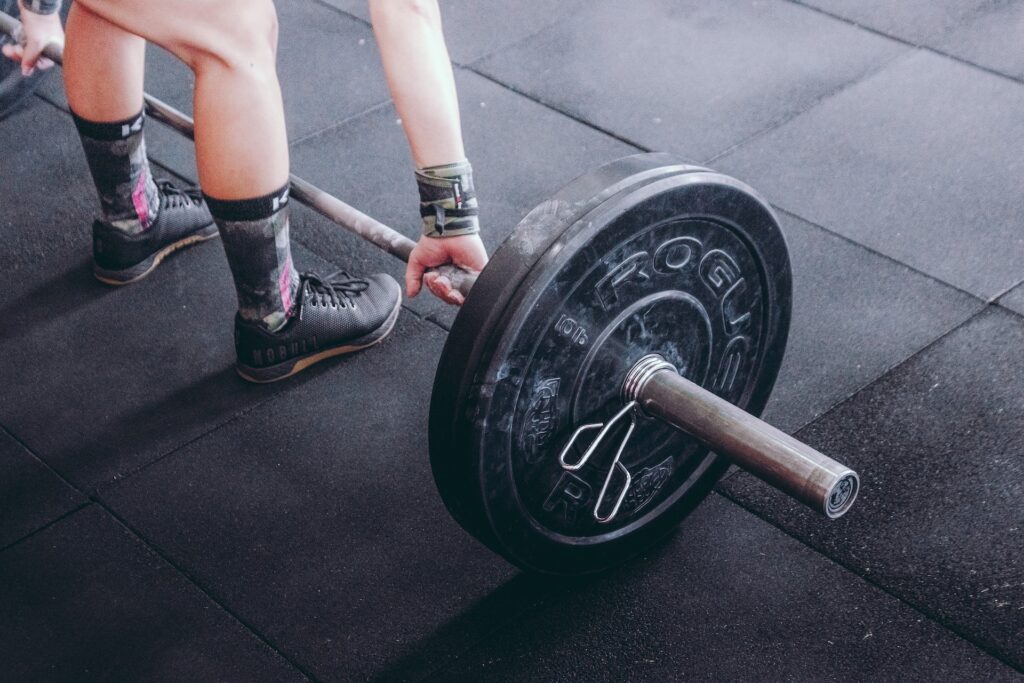 A lifter wearing NOBULL shoes while grabbing a barbell