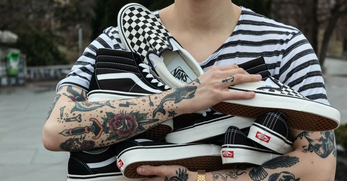 A person holding multiple pairs of Vans shoes